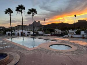 a pool with palm trees and a sunset in the background at Casa Villa Serena in San Carlos