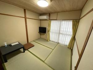 um pequeno quarto com uma mesa e uma janela em Guest House Hamada-en em Tottori