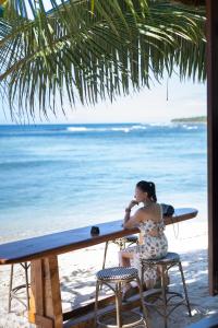 Eine Frau, die an einem Tisch am Strand sitzt. in der Unterkunft Breakas Beach Resort in Port Vila