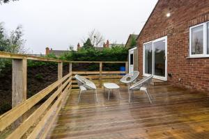 una terraza de madera con sillas y una mesa. en Elegant three bed bungalow en Lincolnshire