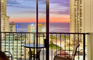 een balkon met een tafel en stoelen en uitzicht op de oceaan bij Jenny's Cottage Waikiki in Honolulu