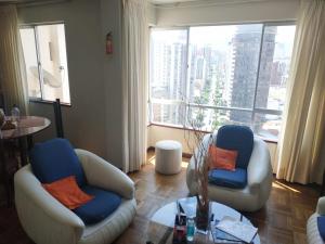 a living room with two chairs and a large window at APARTAMENTO PRIVADO Piso 20a, CENTRICO, CERCA EMBAJADA USA, TELEFERICOS, MALLS, VISTAS 360, SOLEADO, ZONA SEGURA in La Paz +58 photos