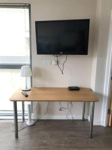a wooden table with a television on a wall at STUDIO Apartment opposite shoreditch Park in London