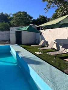 a swimming pool with two chairs and an umbrella at Flores Condominios Depa Lili in Álamos
