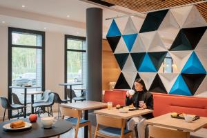 une femme assise à une table dans un restaurant dans l'établissement Holiday Inn Express - Marne-la-Vallée Val d'Europe, an IHG Hotel, à Bailly-Romainvilliers