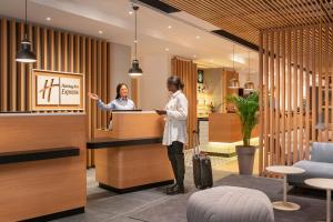 two women standing at a reception desk in a lobby at Holiday Inn Express - Marne-la-Vallée Val d'Europe, an IHG Hotel in Bailly-Romainvilliers