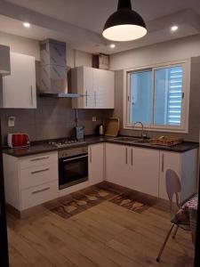 eine Küche mit weißen Schränken und einem großen Fenster in der Unterkunft Schone, ruhige neuwertige, 127 qm Fewo in Sidi Daoud