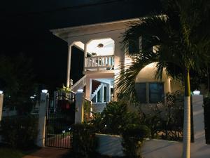 una casa blanca por la noche con una palmera en HCEAS villa is 5 min fr. airport & to the beaches en Bon Accord