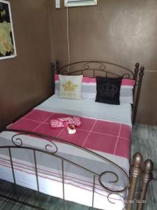 a bed with pink and white sheets and a clock on it at Winterfell Cafe and Private Resort in Bacolod