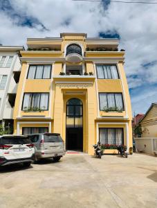 a yellow building with cars parked in front of it at Laluna Guesthouse in Siem Reap