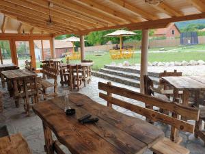 un patio con mesas y bancos de madera y sombrilla en MERAK STD en Vranje