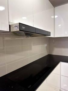 a kitchen with white cabinets and a black stove top oven at The Apple PREMIER CONDO three bedroom in MELAKA in Malacca