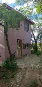 een roze huis met een boom ervoor bij Cabaña Thaqu in Merlo