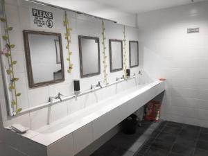 Baño con una fila de lavabos y espejos en Capsule Inn, en Kota Kinabalu