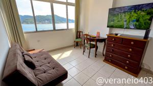 a living room with a couch and a tv and a table at Apartamento frente mar c/ar P/ 6 hóspedes in São Vicente