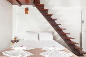 1 dormitorio con 1 cama con sábanas blancas y escaleras de madera en Pousada da Praça Caraíva, en Caraíva