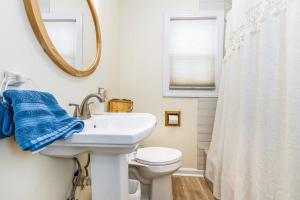 a bathroom with a sink and a toilet and a mirror at Oaklie's Bungalow - Charming Home in Dubuque in Dubuque
