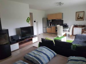 a living room with a couch and a flat screen tv at Ebenerdig mit Terrasse & Garten, WLAN & Parkplatz! Self Check-in & Check-out! Schwedenofen! in Auggen