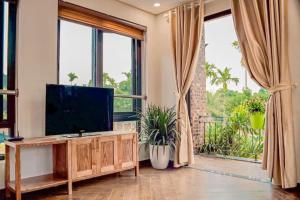 a living room with a flat screen tv and large windows at The Bright House Villa - Venuestay in Hanoi