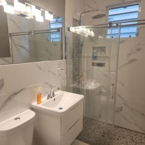 La salle de bains blanche est pourvue d'un lavabo et d'une douche. dans l'établissement Paradise Escape, à Barceloneta