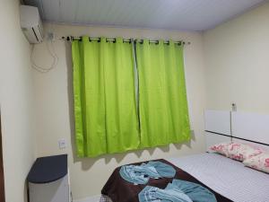 um quarto com uma cortina verde e uma cama em Casa para aluguel de diárias em Foz do Iguaçu