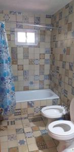 baño con aseo, bañera y ventana en Cabaña Thaqu en Merlo