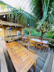 een patio met houten tafels en banken en een palmboom bij Forest View Apartment in Six Huts