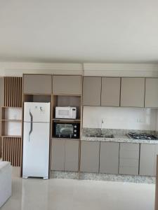 a kitchen with a refrigerator and a microwave at Recanto Meia Praia in Itapema
