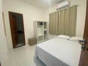 Schlafzimmer mit einem weißen Bett und einem Spiegel in der Unterkunft Casa céu de estrelas in Arraial d'Ajuda