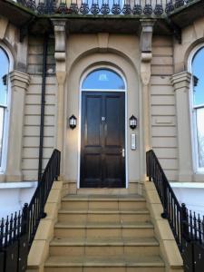 a building with a black door and stairs in front at Brooklands Hideaway in Scarborough