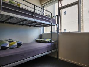 a bunk bed in a room with a window at Newton Lodge Auckland in Auckland