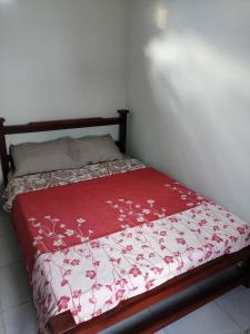 a bed with a red and white blanket on it at hotel Valery in San Gil