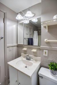 La salle de bains blanche est pourvue d'un lavabo et d'un miroir. dans l'établissement ~Hot Tub~ in a Quiet Home near UofR/Dwnt/Aiprt/RIT, à Rochester