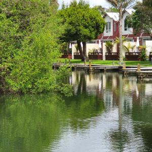 a body of water with trees and houses in the background at Kuirau Chalet Villa 3-bedroom Twin Lake in Rotorua