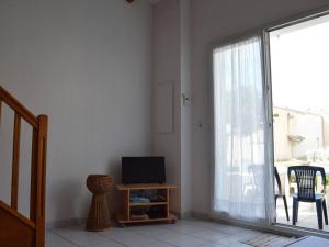 ein Wohnzimmer mit einem TV und einer Glasschiebetür in der Unterkunft Maison Fleury-Saint-Pierre-la-Mer, 2 pièces, 6 personnes - FR-1-229D-352 in Saint Pierre La Mer