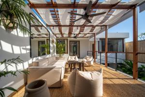 um pátio com mobiliário branco e uma ventoinha de tecto em Green Villa Canggu em Canggu