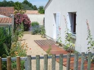 um jardim com um passadiço de madeira ao lado de uma casa em Maison La Tranche-sur-Mer, 3 pièces, 4 personnes - FR-1-22-231 em La Tranche-sur-Mer