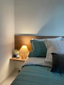 ein Schlafzimmer mit einem Bett mit einer Lampe auf einem Nachttisch in der Unterkunft Flat ESTUDIO de LUXO - Praia de Muro Alto - Piscinas - Ideal para CASAIS, famílias com crianças - ap COMPLETO - AR COND, WI FI, NETFLIX, ESTACIONAMENTO - 400 mt do MAR in Porto De Galinhas + 55 Fotos