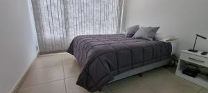 1 dormitorio con 1 cama con manta morada y ventana en Llano del Sur en Ushuaia
