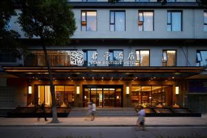 a building with people walking in front of it at SSAW Boutique Hotel Yangzhou in Yangzhou