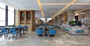 a restaurant with blue chairs and tables and a bar at SSAW Boutique Hotel Yangzhou in Yangzhou