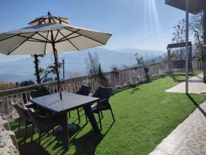 a table and chairs with an umbrella on a lawn at Vacay Datcha in Kūd