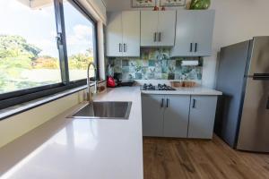 uma cozinha com armários brancos, um lavatório e uma janela em Beach Apartment Villas Jubey, Emotion access em Juan Dolio