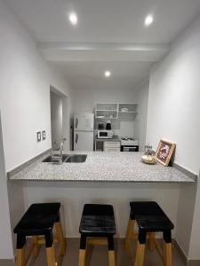 萨尔塔Monoambiente Bambú, Nuevo, amplio y cómodo的厨房配有带2把凳子和水槽的台面