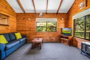 a living room with a blue couch and a tv at Beau Cabin One Bedroom Cabin on Golf Course in Kangaroo Valley