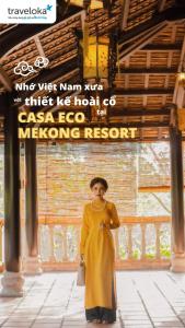 una mujer con un vestido amarillo de pie bajo una señal en CASA ECO Mekong Homestay, en Can Tho