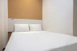 1 cama blanca con 2 almohadas en una habitación en Twospaces Living at Kertajaya Residence, en Bagongsabrangan