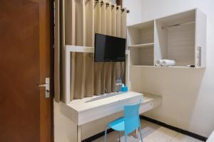 Habitación con escritorio, TV y silla azul. en Twospaces Living at Kertajaya Residence, en Bagongsabrangan