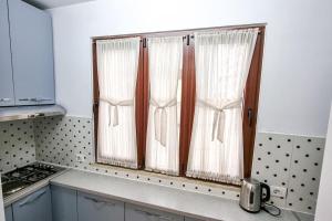 a kitchen with two windows with white curtains at City Center 2BR Apartment in Tirana +13 photos