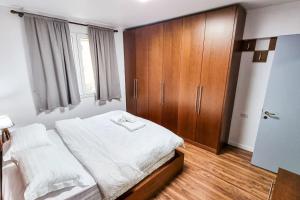 - une chambre avec un lit et une armoire en bois dans l'établissement City Center 2BR Apartment, à Tirana